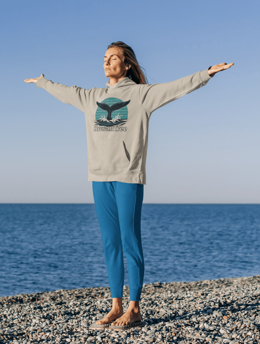 RowanTree Whale Song Pullover Hoodie - RowanTree ClothingPerson wearing a hoodie with a whale graphic on a beach