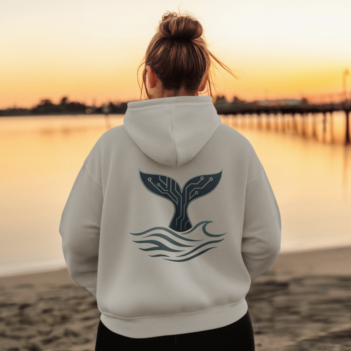 Woman wearing the RowanTree Whale Circuitry  hoodie overlooking a lake, symbolizing harmony between technology and nature.